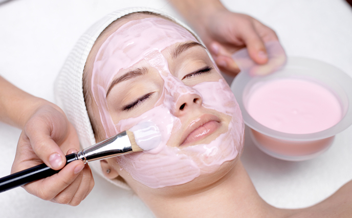 Girl receiving cosmetic pink facial mask